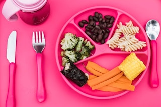 Lifestyle image of the green sprouts learning dining plate in the color pink with various food groups