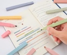 a hand highlighting test in a book with colorful highlighters
