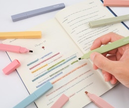 a hand highlighting test in a book with colorful highlighters