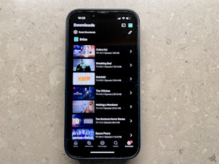iPhone with the Netflix app open showing a list of downloaded tv shows and movies