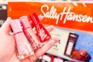 person holding 3 sally hansen nail polishes by the display
