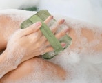a person using a green body scrubber on their leg