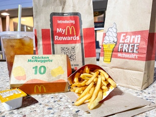 A 10-piece chicken McNugget meal sitting on a table outside of a McDonald's storefront.