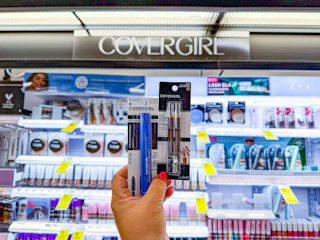 person holding covergirl mascara and eyeliner in front of the display