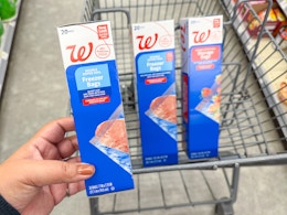 hand holding a pack of storage bags and two packs in a cart