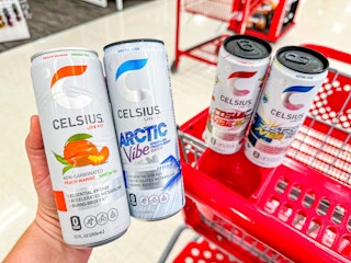 hand holding 2 celsius energy drinks in front of a target cart