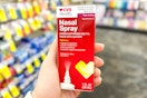 person holding a box of cvs health nasal spray in an aisle