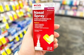 person holding a box of cvs health nasal spray in an aisle
