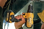 Man using the DEWALT 20V Max Cordless Drill/Driver Kit, 2 Batteries and Charger Included (DCD771C2).