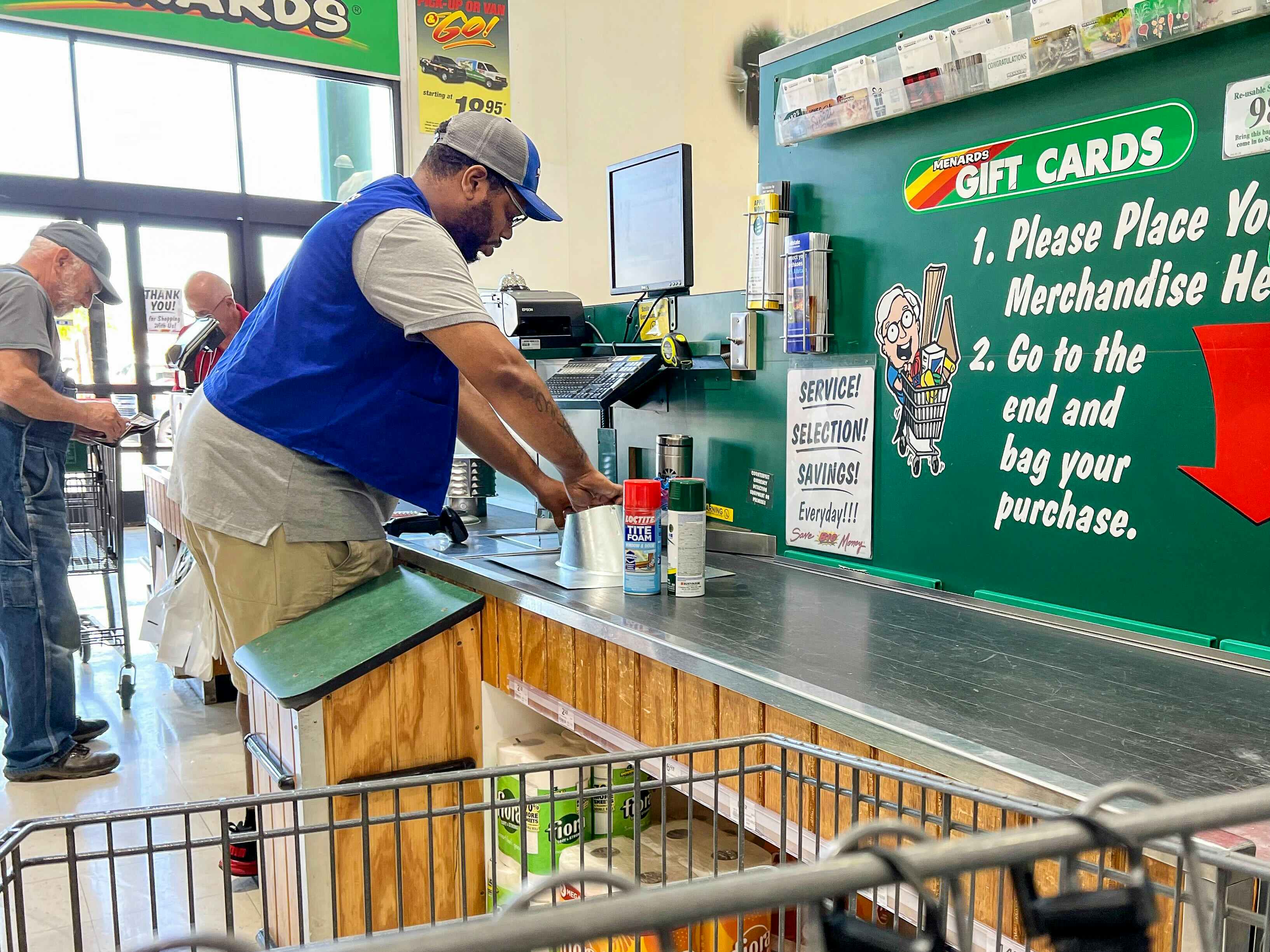 A Menards employee scanning items at the checkout lane.