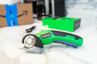 a person using electronic scissors on cardboard