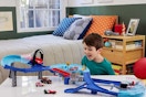 a boy playing with a mattel disney pixar cars set