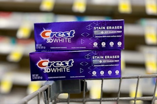two boxes of crest toothpaste balancing on edge of shopping cart