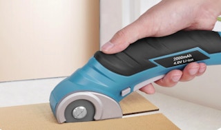 a person using an electric cardboard cutter on cardboard