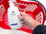 hand holding a bottle of dove hand wash over a target basket