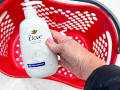 hand holding a bottle of dove hand wash over a target basket