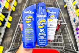 person holding 3 coppertone sunscreens over a cart