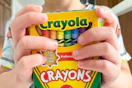 young child holding crayola crayon box