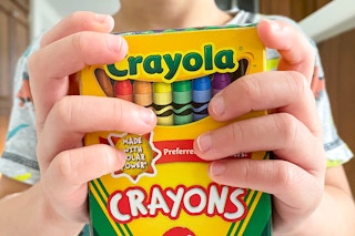young child holding crayola crayon box