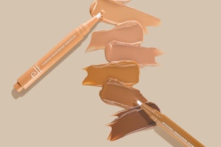 sticks of elf concealer with tone swatches on a tan background
