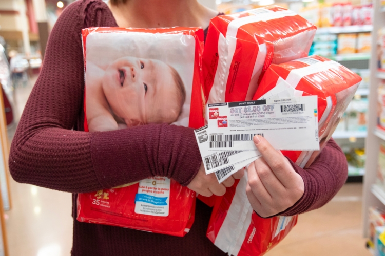A person holding packages of baby diapers and coupons.