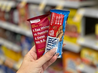 Hand holding an RXBAR and Nutri-Grain bar in aisle