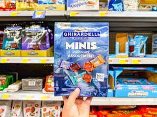 hand holding a bag of ghirardelli minis in walmart aisle