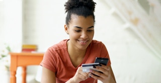 woman holding cash-back credit card and phone