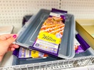 hand grabbing a wilton baking pan with lid off a target shelf