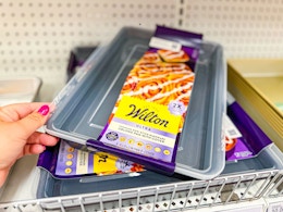 hand grabbing a wilton baking pan with lid off a target shelf