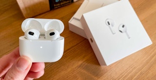 apple air pod pro being held next to amazon box