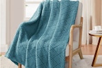 Whale Flotilla Fuzzy Fleece Throw Blanket draped across an accent chair.