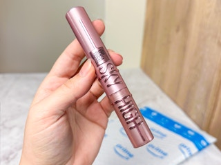hand holding Maybelline sky hight mascara over Prime bag