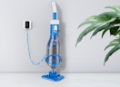 a blue pool vacuum charging against a wall