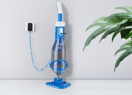 a blue pool vacuum charging against a wall