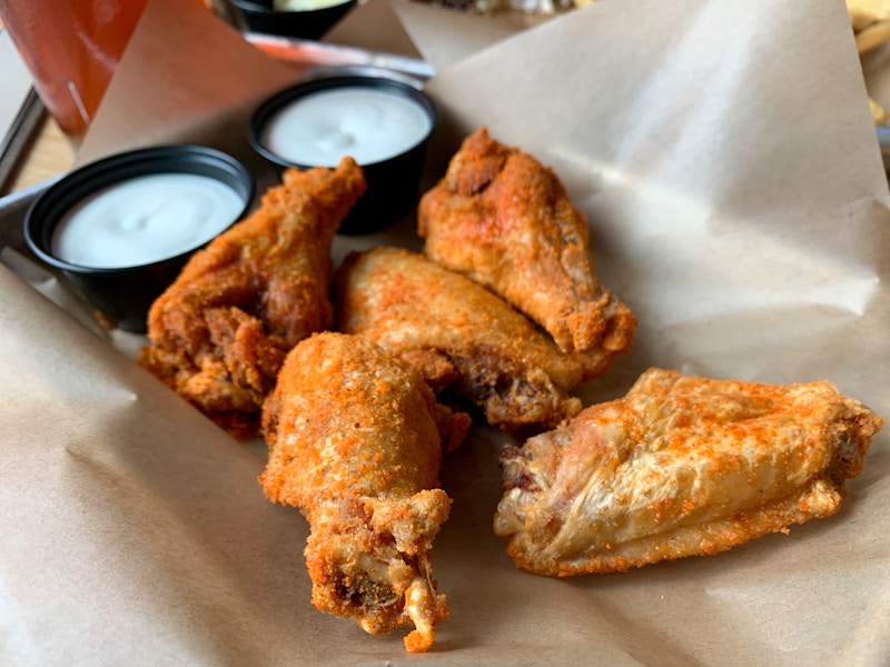 Dry rub seasoning on traditional buffalo wings next to ranch on a platter.