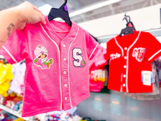 hand holding a strawberry shortcake toddler baseball jersey in walmart