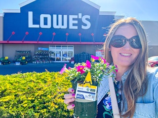 a woman holding a free flower outside Lowes for members rewards