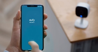 A phone next to a Eufy security camera inside a home.