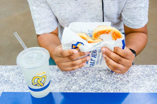 Person holding an Auntie Anne's Pretzel with a lemonade drink