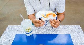 Person holding an Auntie Anne's Pretzel with a lemonade drink