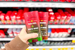 person holding old spice deodorant in front of the shelf