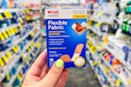 person holding a box of bandages in an aisle