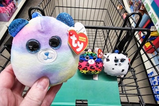 person holding a ty squishy beanie with 2 more in a cart