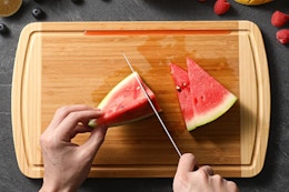 Person cutting watermelon on the HIWARE Large Wooden Cutting Board.