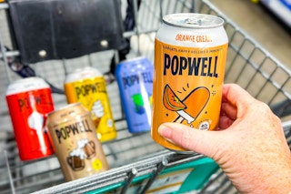 hand holding a can of popwell soda