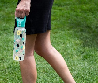 a person holding a glass water bottle with flowers