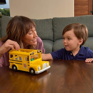 A woman and young boy playing with a CoComelon yellow school bus toy.