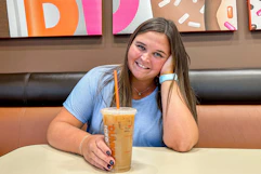 a person smiling with coffee inside of dunkin