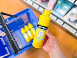 hand holding a spray bottle of Neutrogena sunscreen
